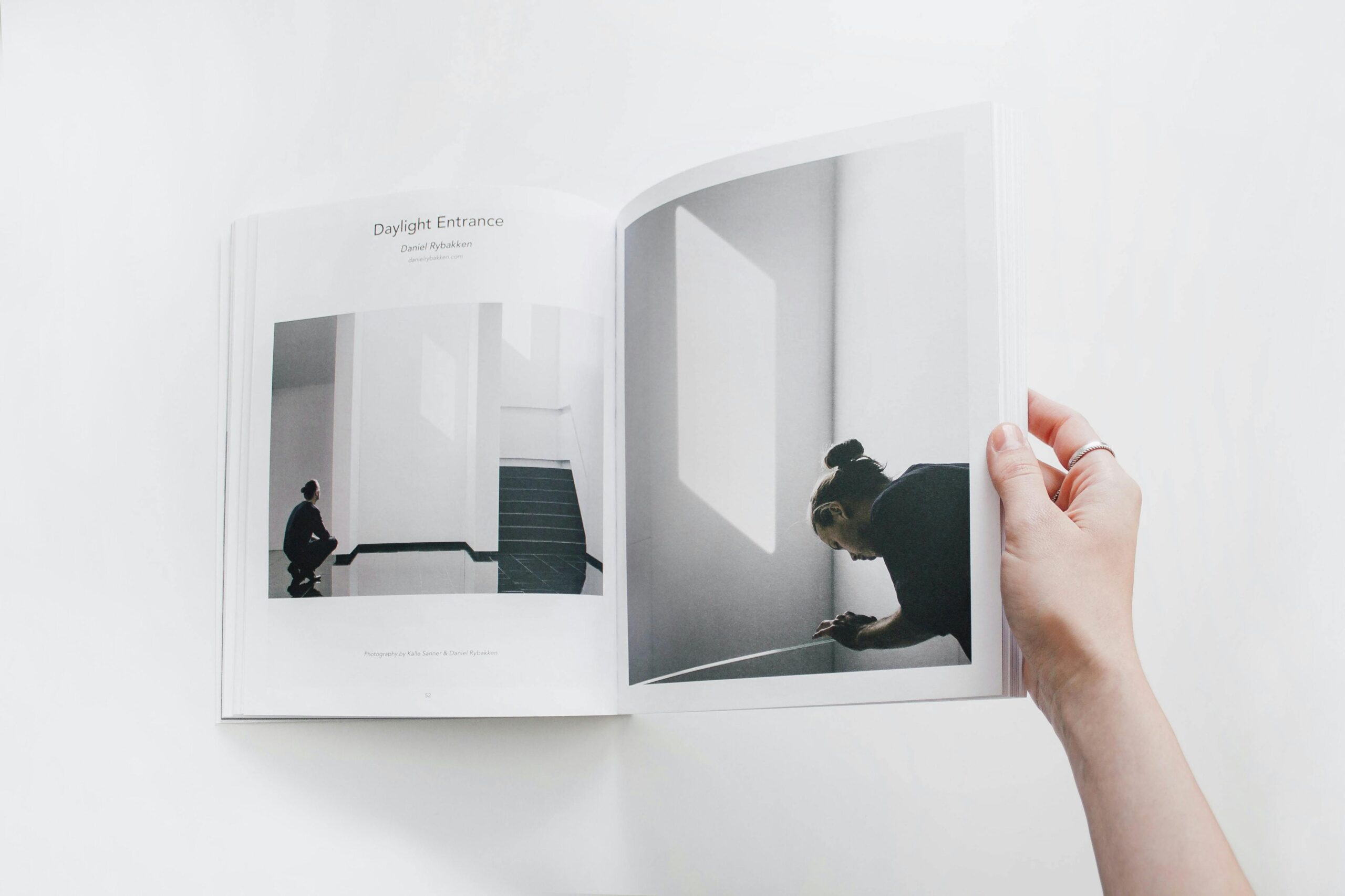 Home An open photography book showing minimalist design, held by a hand.